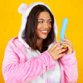 A person wearing a pink, fuzzy bear-themed hoodie with ears smiles while holding the Cute Little Fuckers Trinity - Teal. The background is a solid bright yellow.